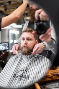 Man receiving a beard trim at a contemporary barbershop, focusing on grooming and style.